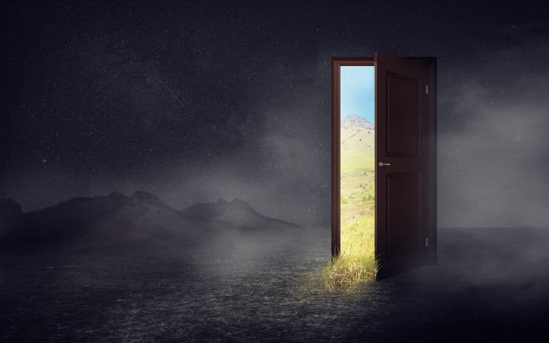 dark world with cracked door open with another beautiful world inside