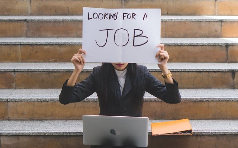 lady holding a need job sign